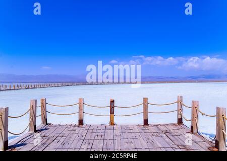 Sul vasto lago salato si trovano lunghi marciapiedi in legno. Il bellissimo scenario del lago salato di Chaka è in estate nella provincia di Qinghai, in Cina. Foto Stock