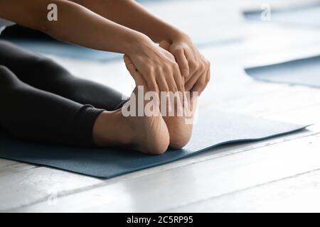 Primo piano donna giovane in posizione seduta in curva in avanti. Foto Stock