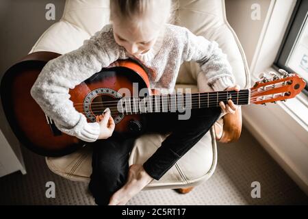 Una giovane caucasion che pratica a suonare la sua chitarra Foto Stock