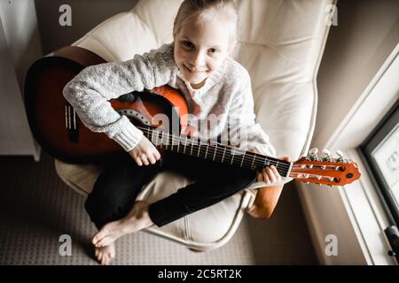 Una giovane caucasion che pratica a suonare la sua chitarra Foto Stock