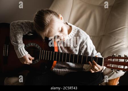 Una giovane caucasion che pratica a suonare la sua chitarra Foto Stock