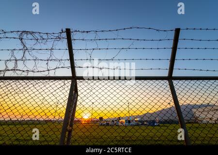 Recinzione di sicurezza dell'aeroporto al tramonto. Foto Stock