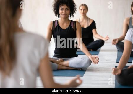 Felice giovane afroamericana seduta in loto. Foto Stock