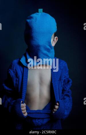 Studio ritratto di un ragazzo in una giacca a maglia blu senza bottoni, Balaclava blu, girata sull'orecchio sinistro. Aprire il torace e l'addome. Foto Stock