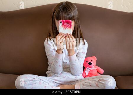 Ragazza di otto anni che gioca su un cellulare Foto Stock