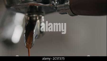 estrazione della shot di espresso con portafiltro a beccuccio singolo dalla macchina da caffè primo piano Foto Stock