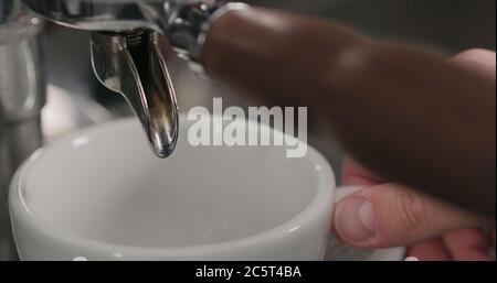 estrazione della shot di espresso con portafiltro a beccuccio singolo dalla macchina da caffè primo piano Foto Stock