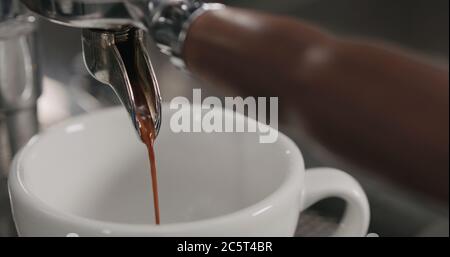 estrazione della shot di espresso con portafiltro a beccuccio singolo dalla macchina da caffè primo piano Foto Stock