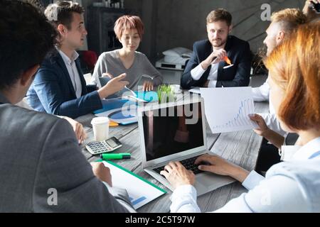 Concetto di team di pianificazione aziendale, persone sedute intorno al tavolo dell'ufficio e che lavorano con i report dei dati finanziari Foto Stock