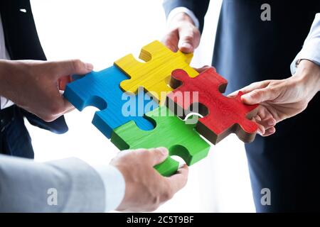 Team di persone di affari che raggruppa quattro pezzi di puzzle di colore idee di cooperazione di unità concetto Foto Stock