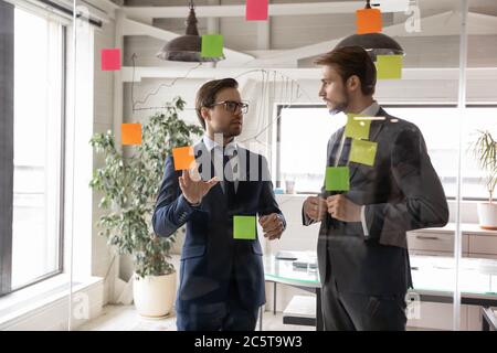 Gli imprenditori focalizzati brainstorm sviluppare idee su vetro parete di ufficio Foto Stock