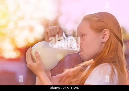 La ragazza beve latte fresco. Felice giovane donna che beve latte. Bevanda sana del latte. Foto Stock