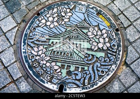 Una copertura di tombino ad Osaka con motivi tradizionali. Foto Stock