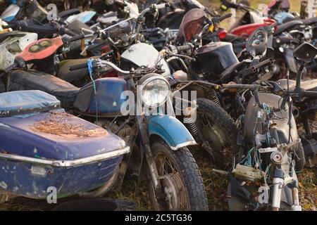 Le vecchie biciclette arrugginite, moto, auto giocattolo, motori, pneumatici e ruote con raggi all'aperto a terra Foto Stock