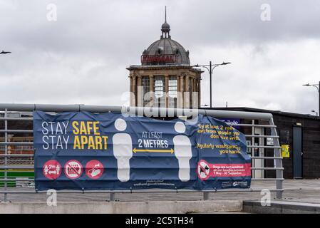 Sede dell'evento Kursaal a Southend on Sea, Essex, Regno Unito. Chiuso e decadente. COVID-19 banner di distanza sociale Coronavirus. Rimani al sicuro, stai a parte slogan 2 m. Foto Stock