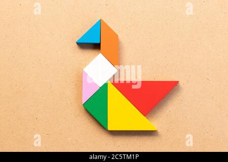 Puzzle tangram colore in cigno o anatra forma su legno bacground Foto Stock