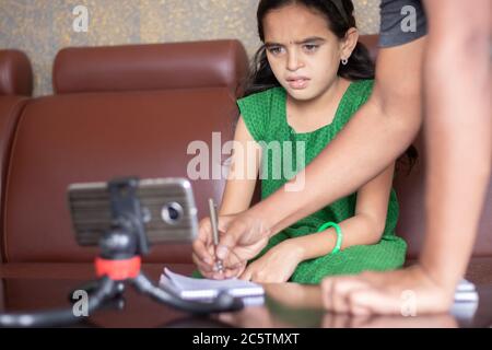 Padre aiutare la figlia risolvendo il problema mentre studia la lezione da classe online o e-learning - concetto di ruolo dei genitori nel sostenere il bambino Foto Stock