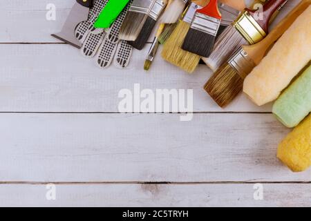 Attrezzi di verniciatura vari rulli di spazzole di vernice sul tavolo di legno Foto Stock