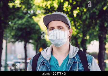 Uomo caucasico trent'anni in maschera medica passeggiate attraverso il parco in estate. Foto Stock