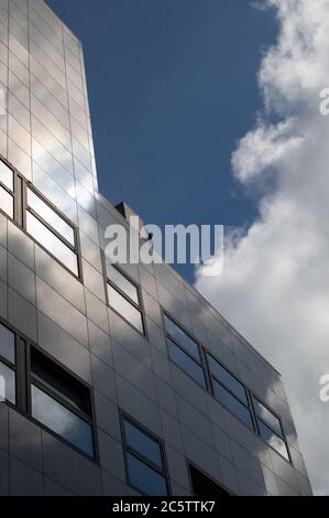 Luce del sole e nuvole che si riflettono in un moderno edificio per uffici Foto Stock