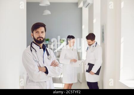 Un gruppo di operatori sanitari guarda un'immagine dai raggi X in piedi a una finestra in un ospedale. Foto Stock