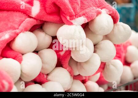 Plaid rosa con pomponi bianchi. Un accessorio caldo per un autunno accogliente. Foto Stock