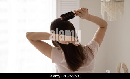 Vista posteriore giovane donna pettinando capelli lisci lunghi sani Foto Stock