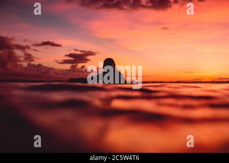 16 aprile 2020. Bali, Indonesia. Surf ragazza relax sulla tavola da surf. Surfisti in oceano durante il surf all'alba o al tramonto. Foto Stock