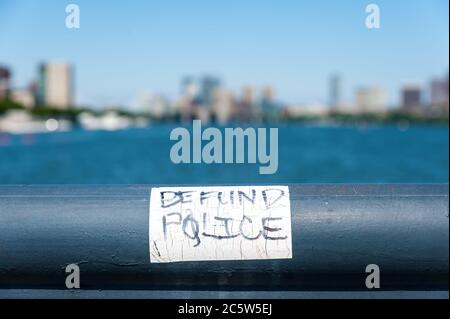 Adesivo della polizia Defund sulla ringhiera in ferro che si affaccia sul fiume Charles e sullo skyline della città di Boston. Foto Stock