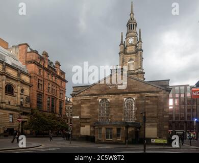 I pedoni camminano oltre la chiesa parrocchiale di St George's Tron, risalente agli inizi del XIX secolo, a Nelson Mandela Place, nel centro di Glasgow, Scozia. Foto Stock