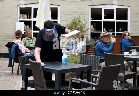 Ironbridge, Shropshire, Regno Unito 5 luglio 2020. Cameriere del ristorante che indossa i tavoli di pulizia della visiera per il prossimo cliente al White Hart a Ironbridge durante la pandemia del virus Covid 19. Credit: David Bagnall/Alamy Live News Foto Stock