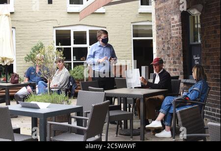 Ironbridge torna alla vita mentre pub, ristoranti e negozi riaprono durante il fine settimana. Un membro del personale del White Hart indossa una maschera facciale che prende o Foto Stock