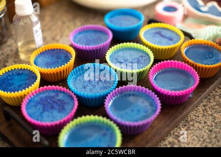 Stampi colorati di cupcake di silicio su boards di legno riempiti di sapone liquido per un hobby fatto in casa di melt e pour soapmaking Foto Stock