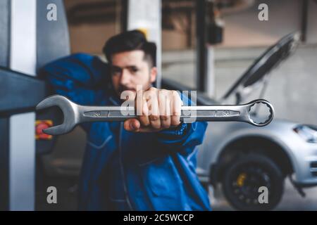 Meccanico automatico con chiave, fuoco selettivo. Concetto di riparazione auto Foto Stock