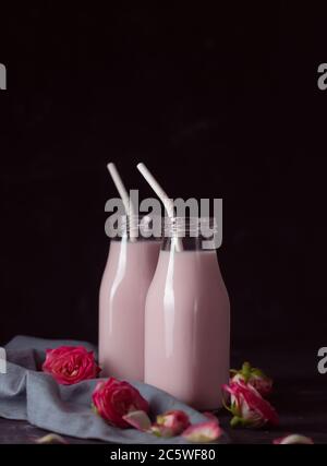 Il latte lunare si prepara con il fiore rosa in due bottiglie su una bla. Drink rilassante alla moda a base di tradizioni ayurvediche Foto Stock