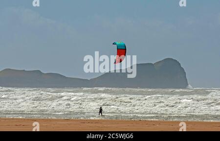 Llangennith Beach, Swansea, Regno Unito. 5 luglio 2020. Un solitario kite surfer sfrutta al massimo le condizioni ventose di fronte alla Worms Head sulla penisola di Gower vicino a Swansea, mentre il blocco in Galles continua. Credit: Phil Rees/Alamy Live News Foto Stock