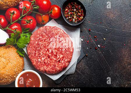 Ingredienti crudi per hamburger, sfondo scuro, spazio per la copia. Sfondo di cottura. Foto Stock