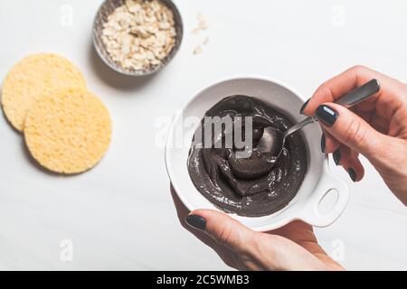 Maschera di cottura di argilla nera e farina d'avena, sfondo bianco. Concetto di cura della pelle. Pelle sana. Foto Stock