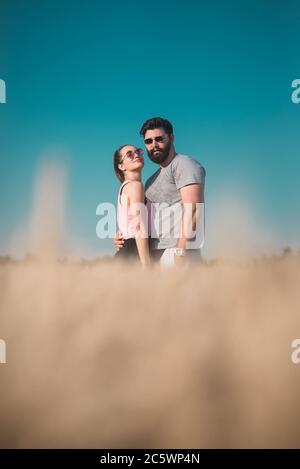 Giovane coppia che si agguanata in campo di grano in estate Foto Stock