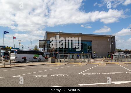 L'esterno o la facciata del terminal dei traghetti internazionali di Portsmouth con un pullman di passeggeri all'esterno Foto Stock