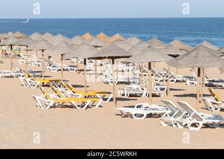 Ombrelloni e amache in fila per il turista in affitto sulla spiaggia di Islantilla Foto Stock