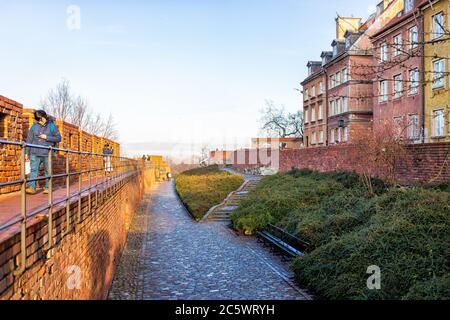 Varsavia, Polonia - 19 dicembre 2019: Famosa fortezza in mattoni barbican nella storica strada della città vecchia nella capitale, nella soleggiata giornata invernale e nel muro rosso arancio Foto Stock