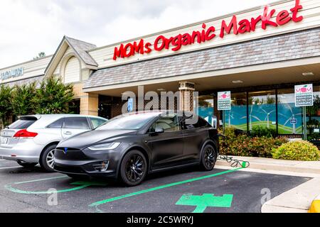 Herndon, USA - 11 giugno 2020: Facciata esterna del negozio MOM's Organic Market sulla strada nella Virginia Fairfax County e Tesla modello X con ricarica per auto al par Foto Stock