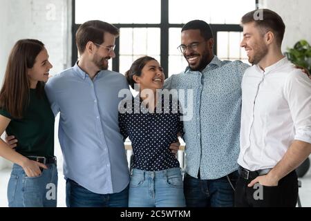 I colleghi entusiasti e diversi che si battono scherzando apprezzano la riunione e l'amicizia Foto Stock