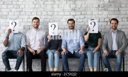 Tre candidati nascondono i loro volti dietro la carta con un punto interrogativo Foto Stock