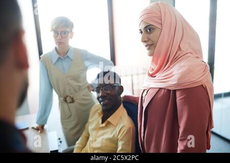 Ritratto di moderno team multi-etnico di affari in piedi da tavolo riunioni in sala conferenze, concentrarsi su donna musulmana indossando il copricapo con African-Ameri Foto Stock