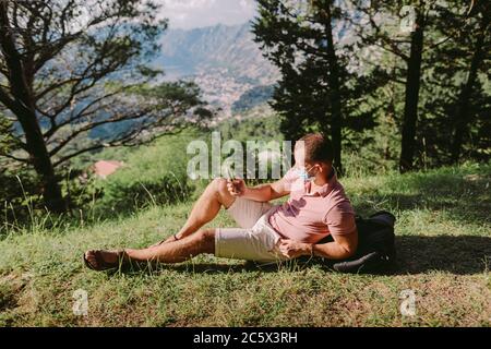 uomo viaggio indossare maschera protettiva in montagna Foto Stock