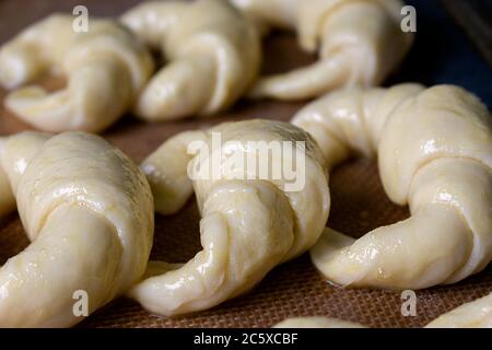 Pronto per la cottura, croissant argentini crudi, medialunas de Manteca su tappetino di pasta al silicio primo piano Foto Stock