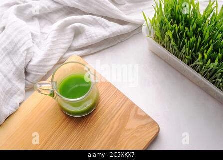 Grano erba sparata sulla tavola di legno e grano erba pianta nel pot.Modern tendenza di salute. Foto Stock