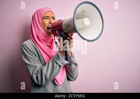 Business arab donna indossare hijab gridando arrabbiato per protesta attraverso il megafono. Urlando eccitato sulla conversazione ludspeaker e urlando le notizie Foto Stock